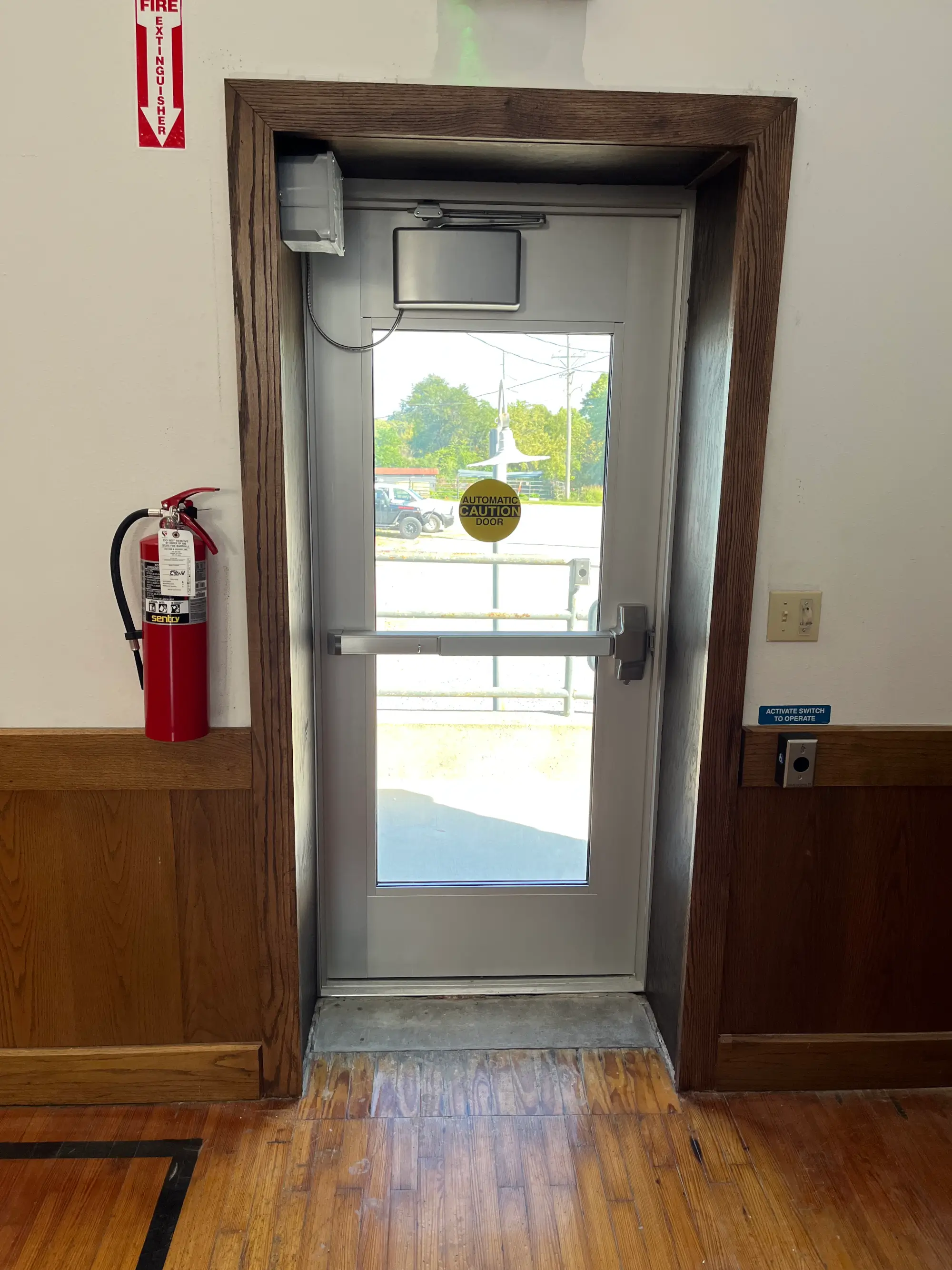 Commercial automatic door operator with push button activation and fire-rated exit hardware.