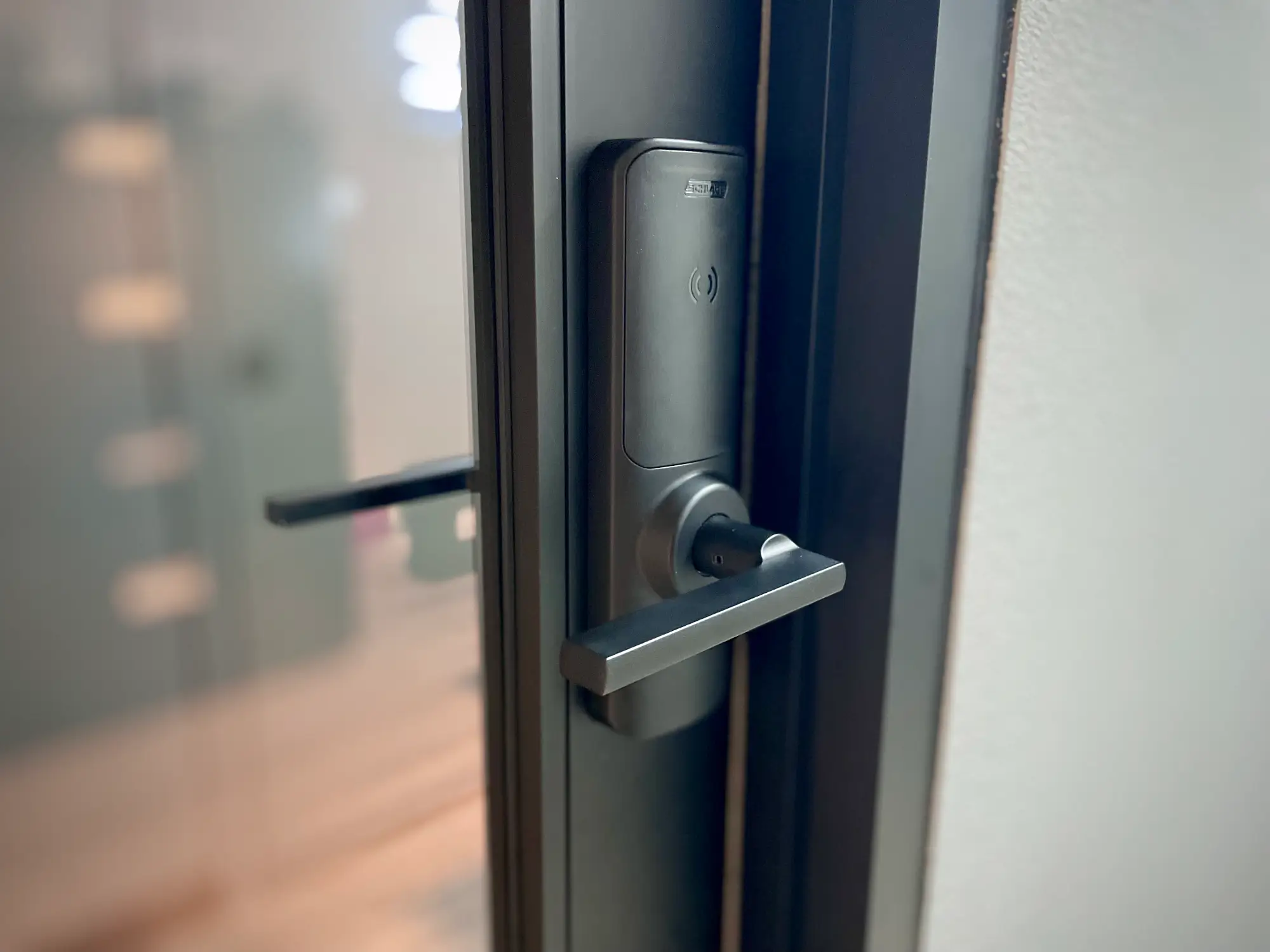 Commercial electronic door lock with keyless access control hardware on a glass office door.