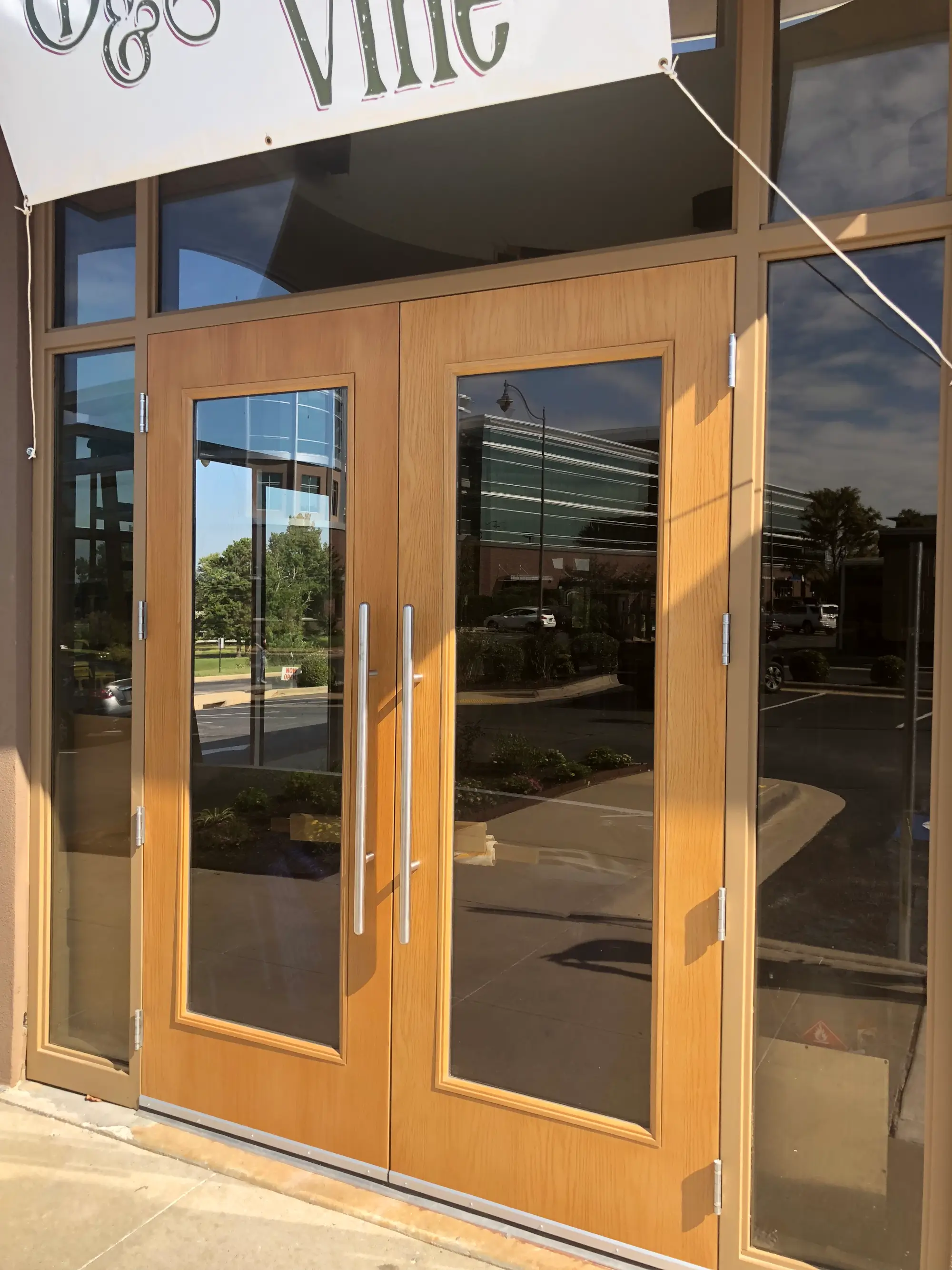 Commercial double door installation with glass panels, pull handles, hinges, and storefront framing.