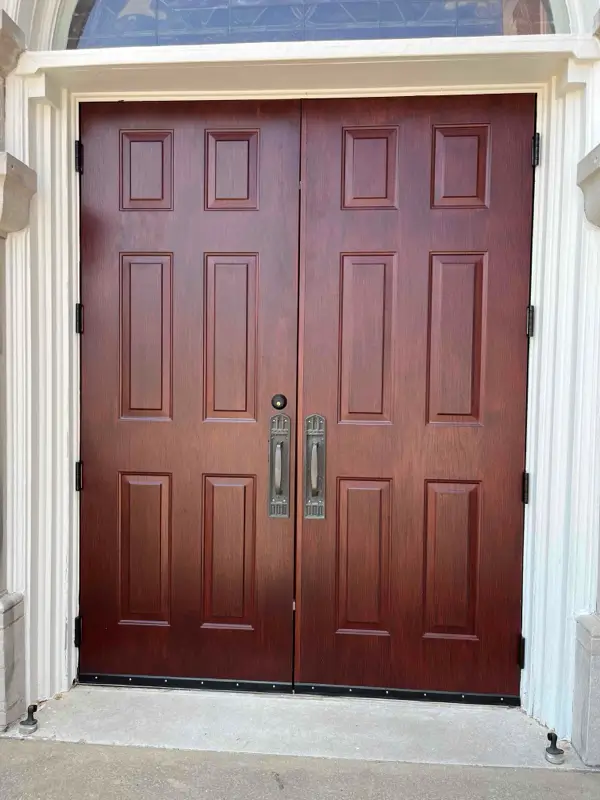 Wood-look commercial double entry doors with pull handles and exterior door hardware.