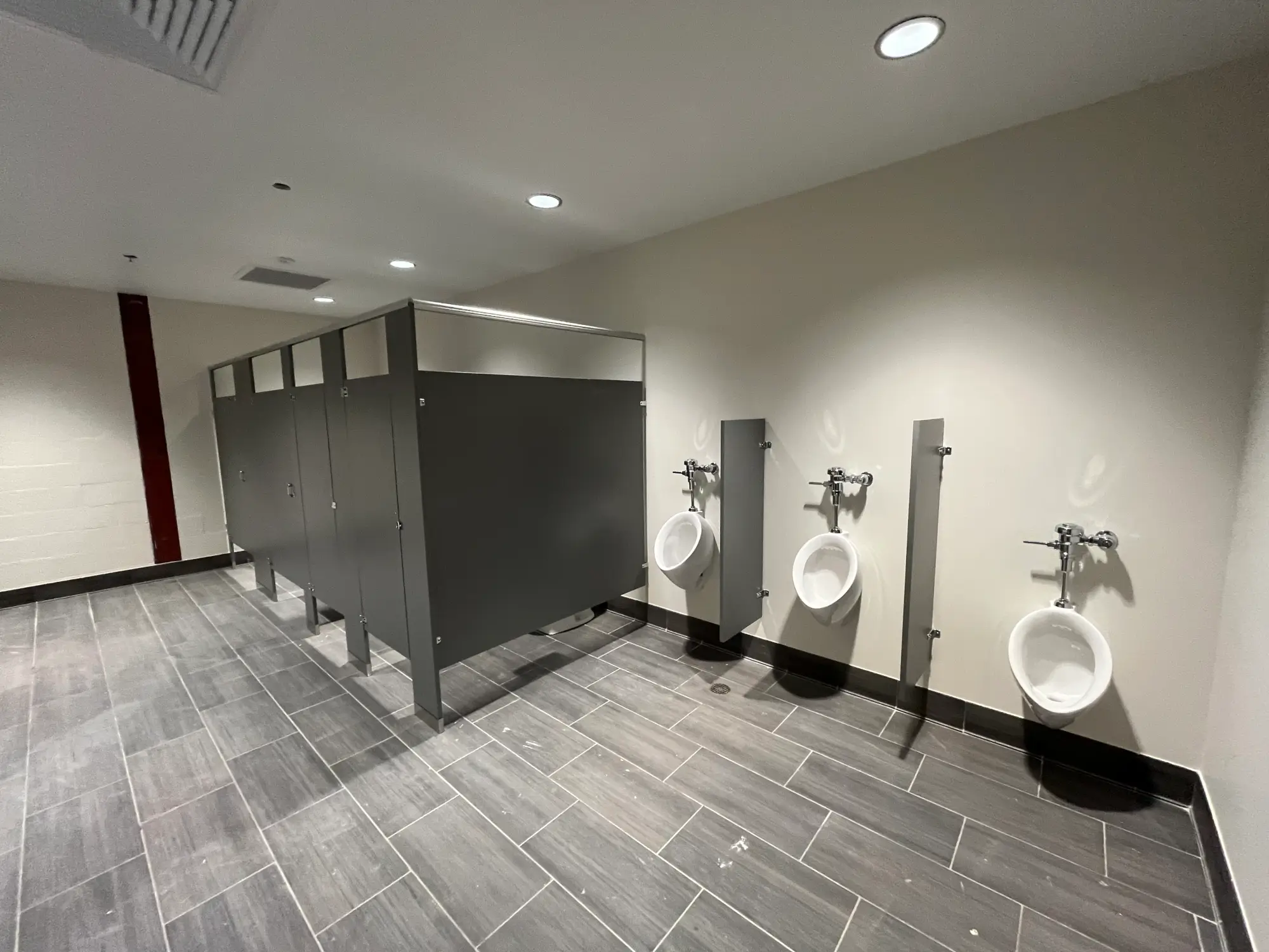 Commercial restroom partitions and urinal screens installed in a modern bathroom.